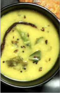 Bowl of Dalithoy (Konkani lentils) - yellow lentils with leaves, seeds and a green chili pod