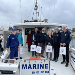Nine people standing on the rear deck of a boat.