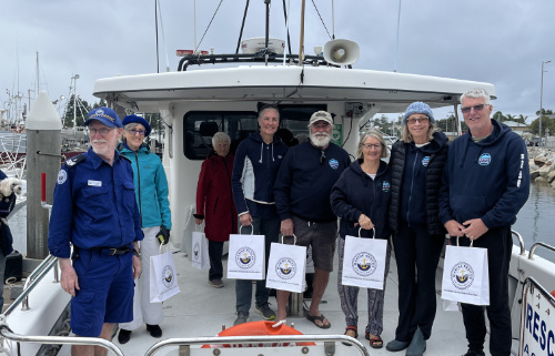 Nine people standing on the rear deck of a boat.