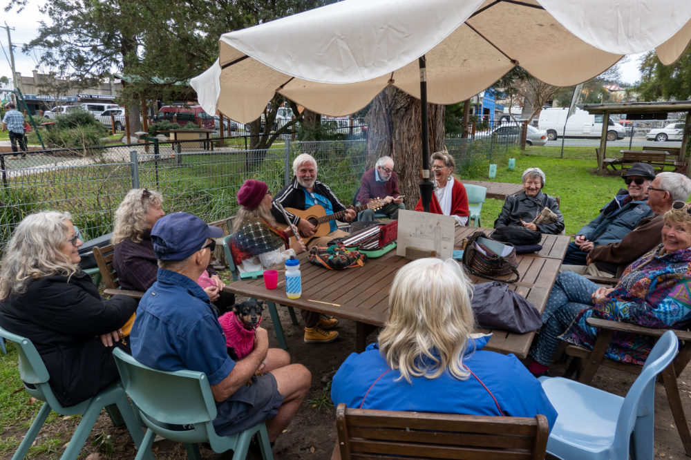 People sitting outdoors around a table under a large umbrella.