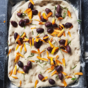 Foccacia dough in flat pan with olives and rosemary