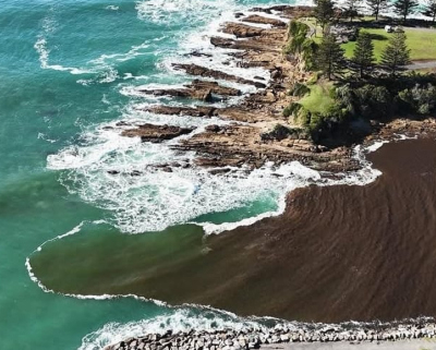 Aerial image of muddy water running into the ocean.