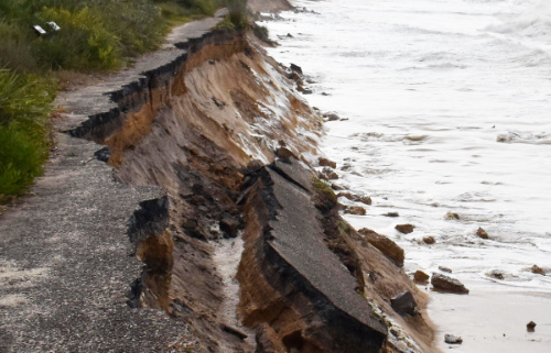 Close up of storm damage to a track running beside the ocean