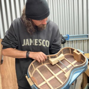 Man holding a guitar body partly completed