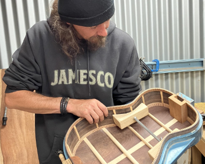 Man holding a guitar body partly completed
