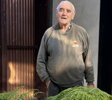 Man standing with a fern in the foreground