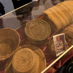 Close-up of woven baskets in a display case with a photograph at the front.