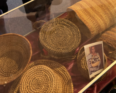 Close-up of woven baskets in a display case with a photograph at the front.