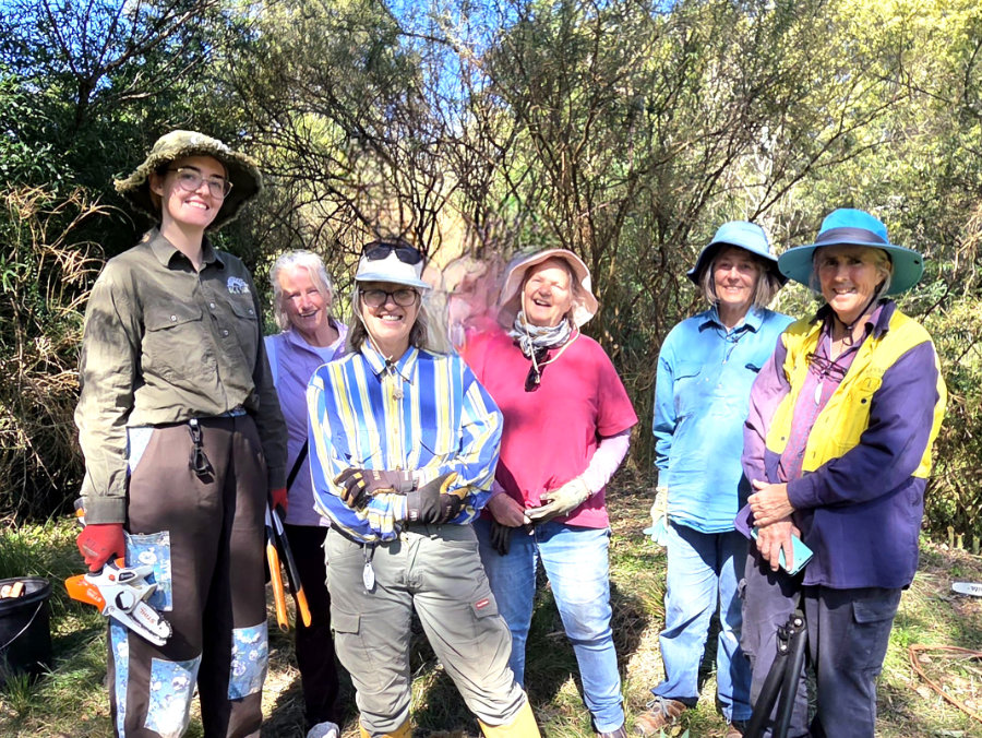 Group of people outdoors dressed in gardening clothes.