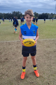Boy holding a yellow AFL football