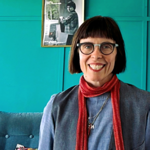 Woman in front of a bright turquoise wall.