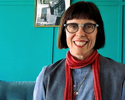Woman in front of a bright turquoise wall.