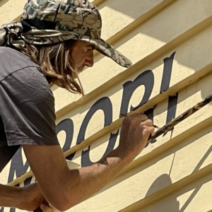 Man painting signage on a yellow wall
