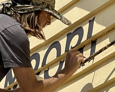 Man painting signage on a yellow wall