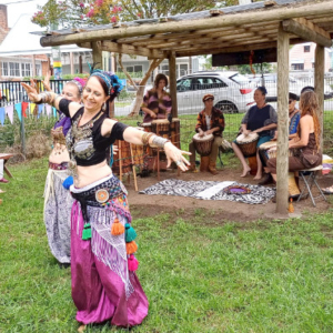 Woman belly dancing with a group of drummers in the background.