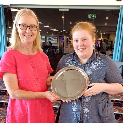 Two women holding their cross-stitch piece.