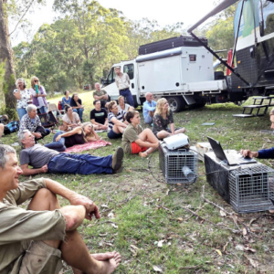 Group seated on the ground listening to a talk