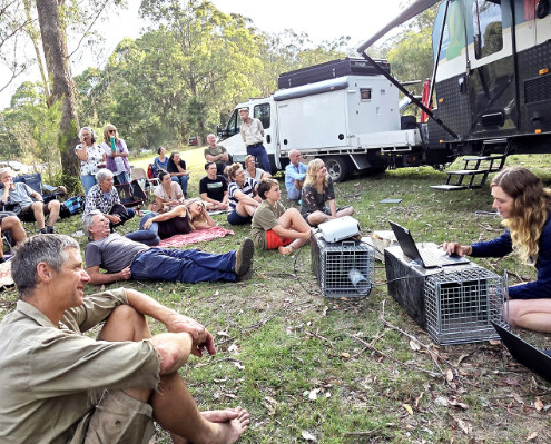 Group seated on the ground listening to a talk