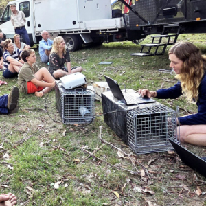 A group sitting on the ground with a speaker in the front.