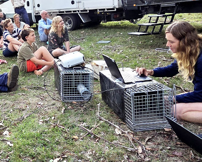 A group sitting on the ground with a speaker in the front.