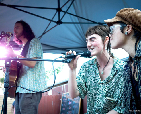 Three people in a band, two singing and one on guitar