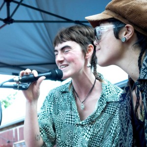 Two women singing at a microphone.