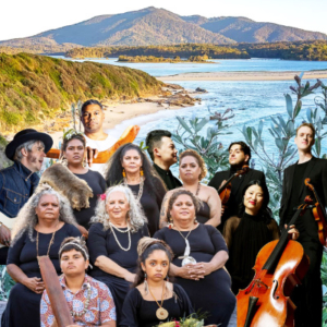 Photo of musicians with their instruments with the shoreline and mountain in the background.