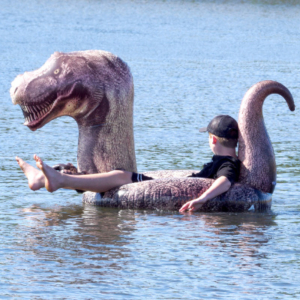 Person floating in a T-Rex inflated boat.