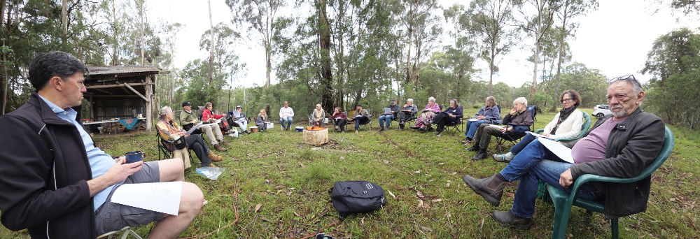 Group of people sitting in a circle outside.