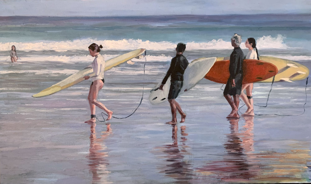Four people on a beach carrying surf boards, one person in the distance in the water