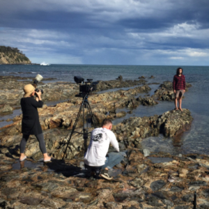 Men filming on a rocky beach