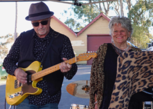 Man with a guitar and woman dressed in leopard patterned clothing.