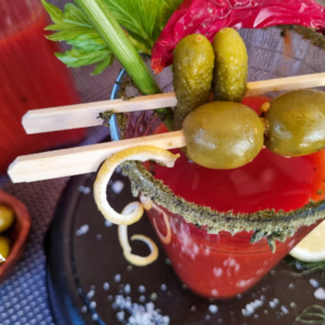 Close-up of a red cocktail with olives across the top