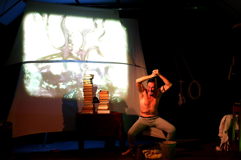 Man on the floor in front of the projected image of an artwork depicting an octopus.