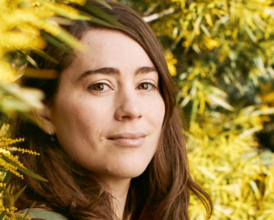 Woman surrounded by yellow wattle flowers.