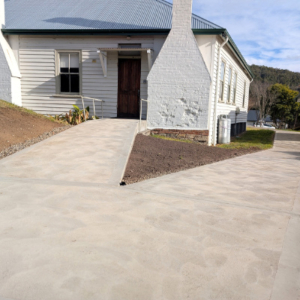 The back entrance to a bulding painted white showing new concrete path for wheelchair access.