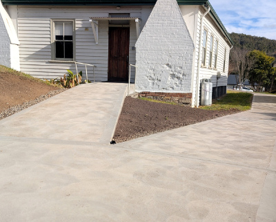 The back entrance to a bulding painted white showing new concrete path for wheelchair access.