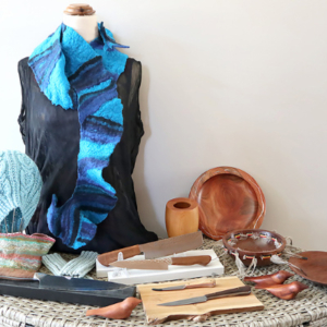 Blue felted scarf drape on a stand with a variety of wooden objects around it.