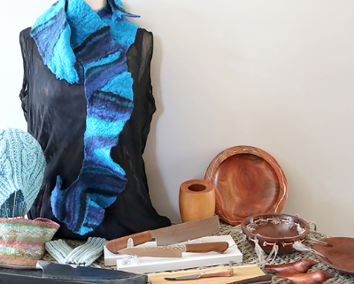 Blue felted scarf drape on a stand with a variety of wooden objects around it.
