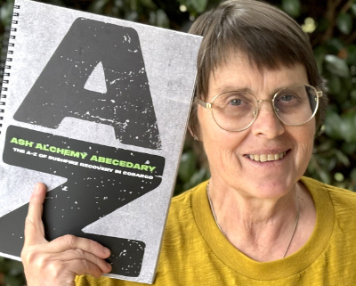 Woman holding a book with very large letters AZ on the cover.