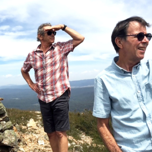 Two men using their hands as shade, looking into the distance