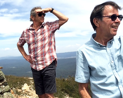 Two men using their hands as shade, looking into the distance