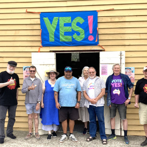 Group of people standing under a large YES! sign